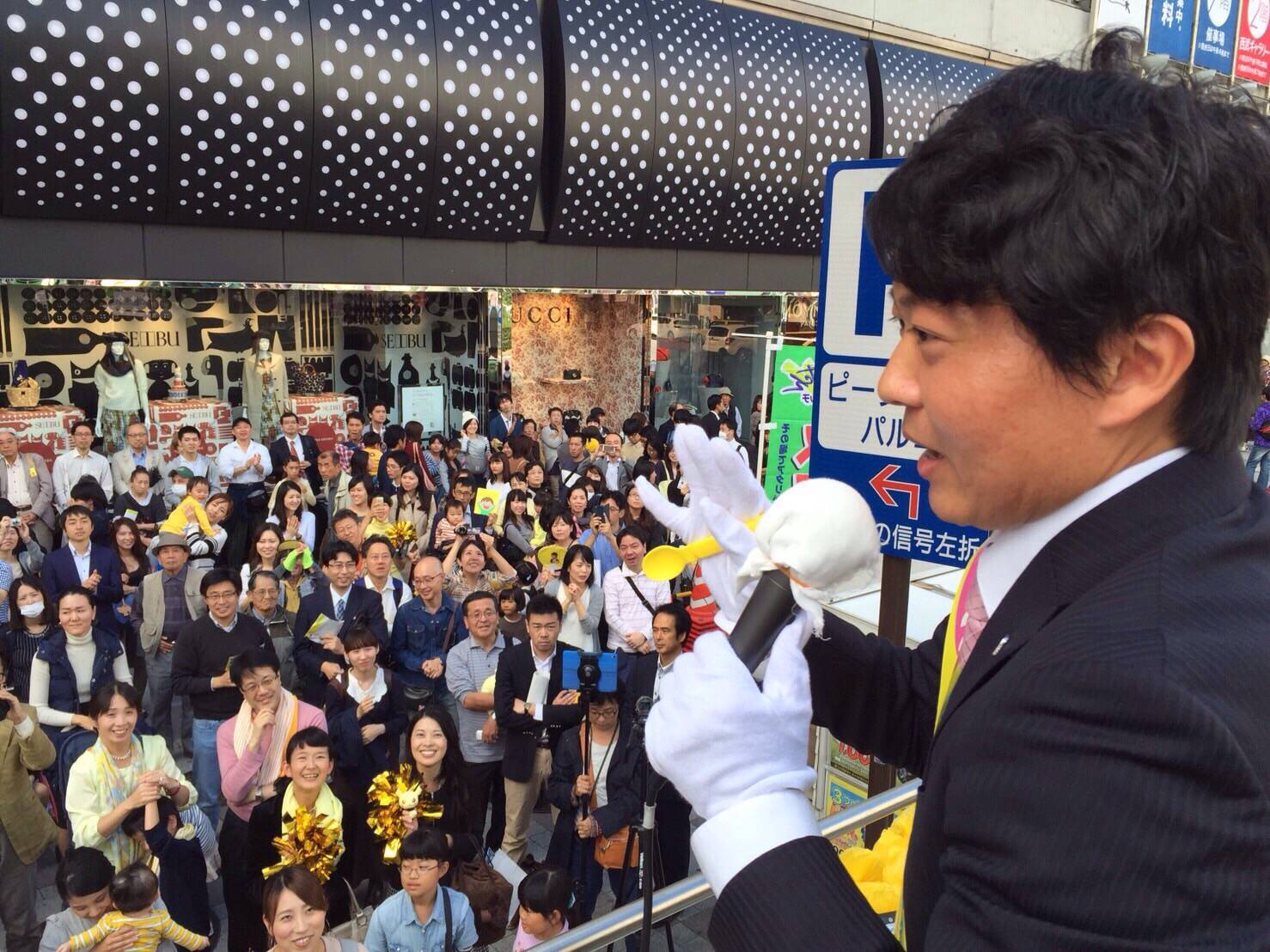 吉井氏の演説の風景。右手にはなぜか黄色いスプーンを持っている